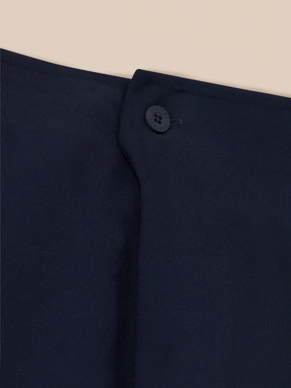 Close up of navy golf trousers waistband button embossed with Castore logo