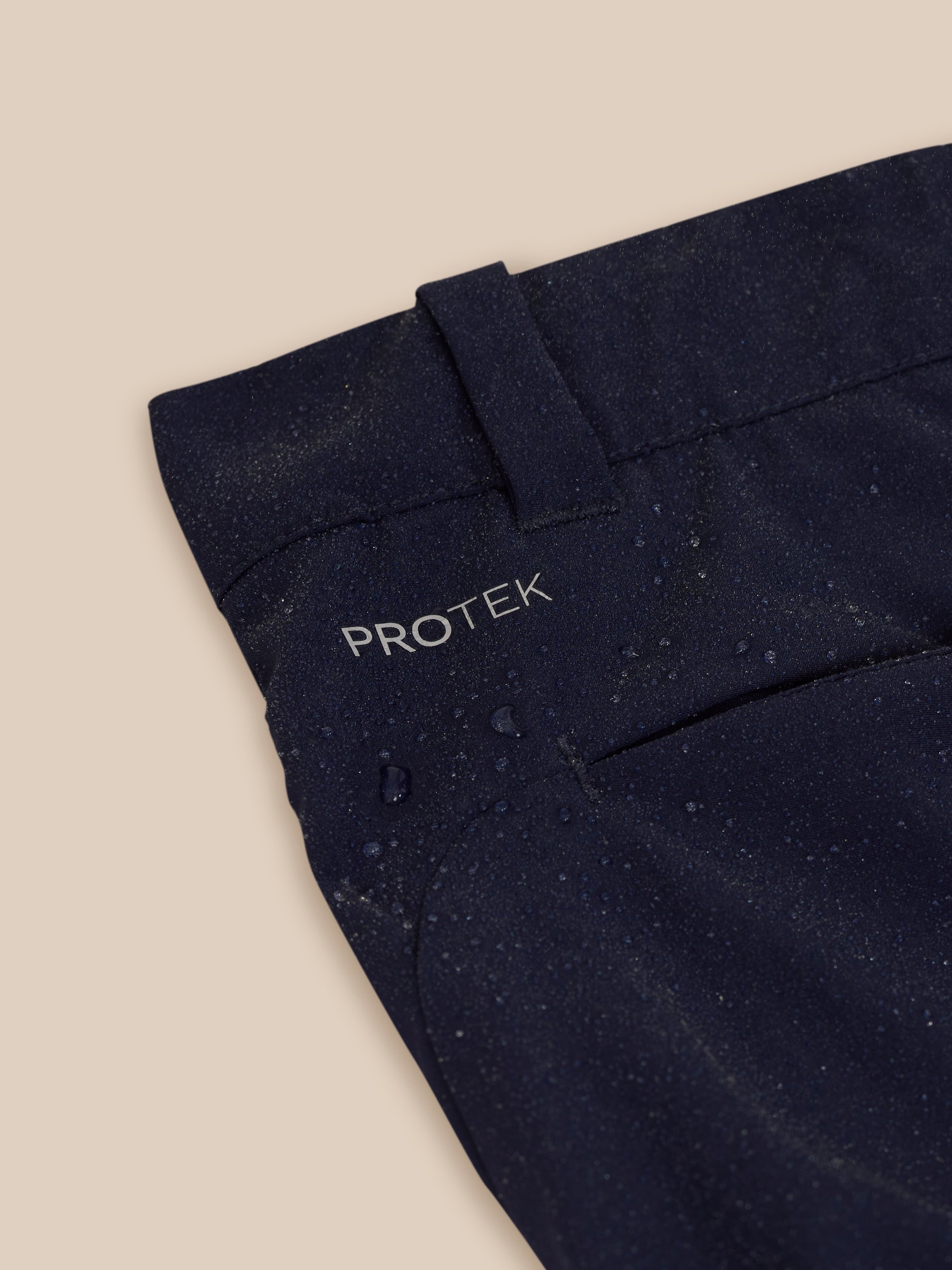 Close up of navy golf trousers waistband area with ProTek branding and zipper detail