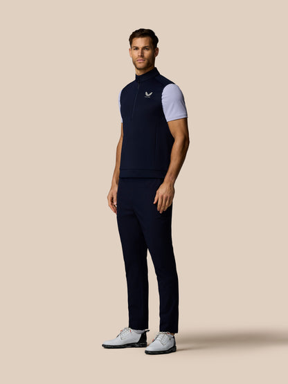 Front view of a man wearing navy Castore Golf Flex Half Zip Gilet with white sleeves and Castore logo on the left chest