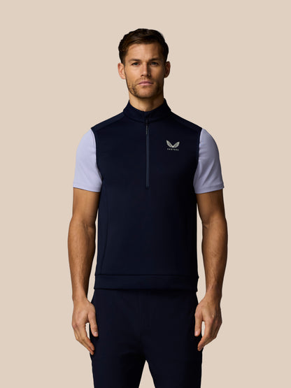 Front view of a man in navy Castore Golf Flex Half Zip Gilet with white sleeves and Castore logo on the chest