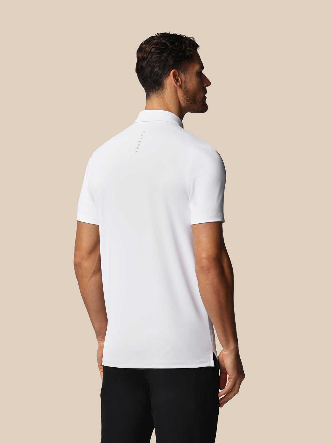 Man wearing a white polo shirt against a beige background