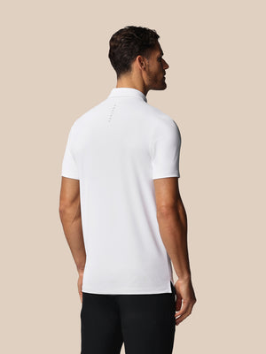 Man wearing a white polo shirt against a beige background
