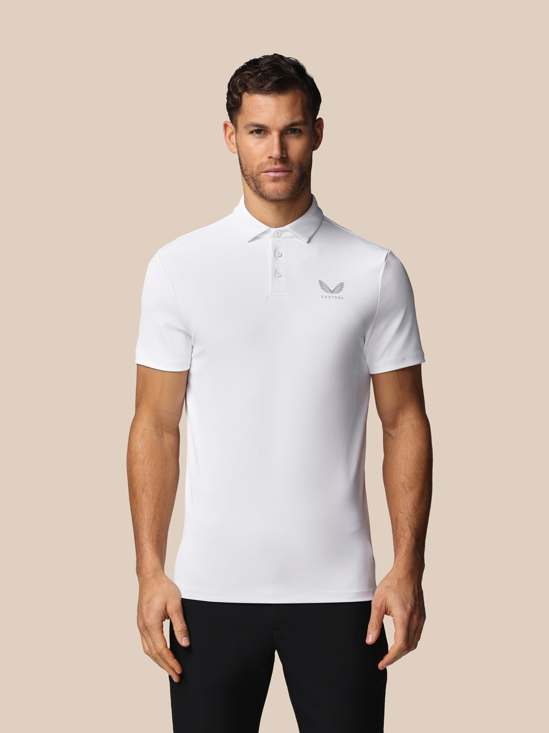 Man wearing a white polo shirt with a Castore logo on a beige background