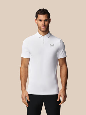 Man wearing a white polo shirt with a Castore logo on a beige background