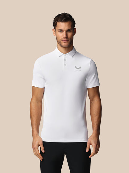 Man wearing a white polo shirt with a Castore logo on a beige background
