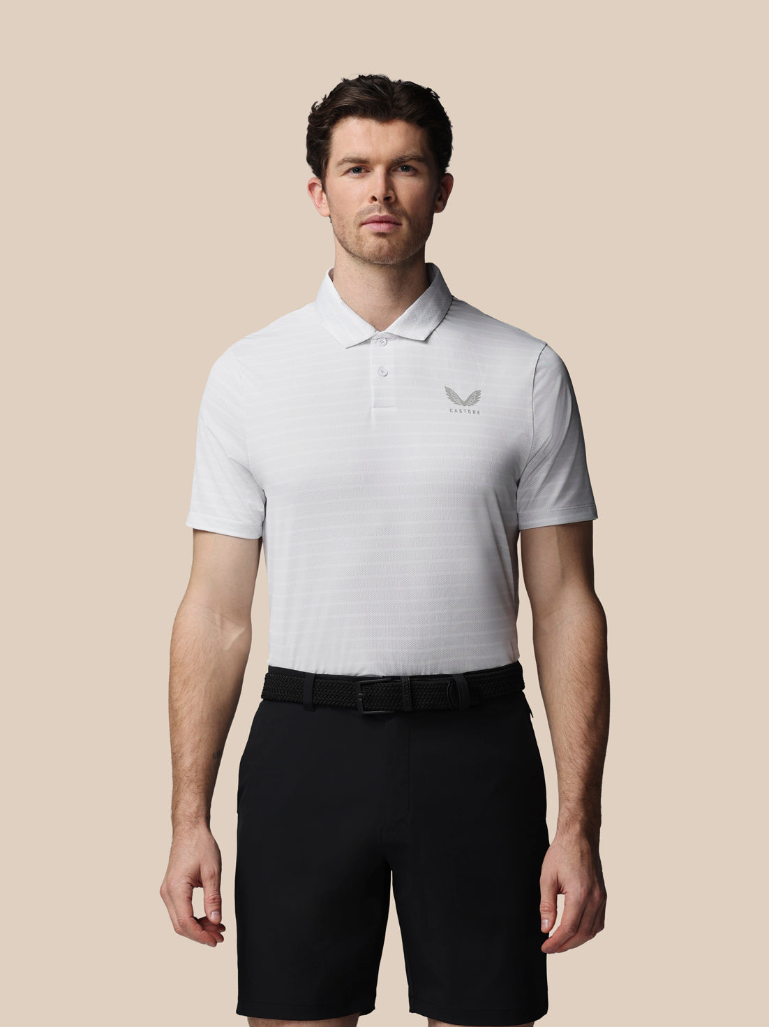 Man wearing a white polo shirt with a logo on a beige background