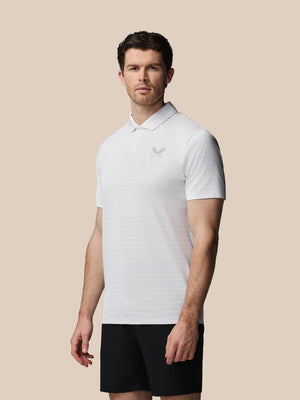 Man wearing a white polo shirt with a logo on a beige background