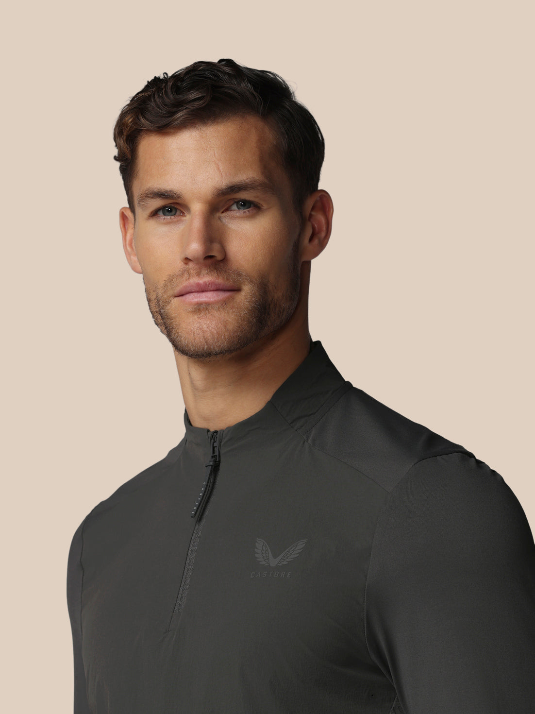 Front view of a man wearing a dark charcoal LVS Quarter Zip Long Sleeve Top with zip collar and Castore logo.