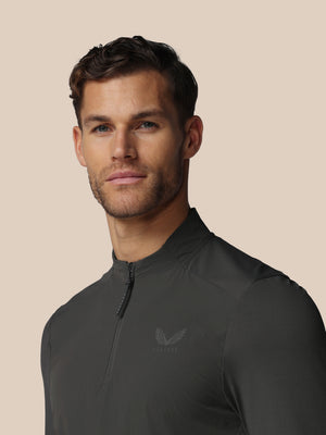 Front view of a man wearing a dark charcoal LVS Quarter Zip Long Sleeve Top with zip collar and Castore logo.