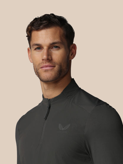 Front view of a man wearing a dark charcoal LVS Quarter Zip Long Sleeve Top with zip collar and Castore logo.