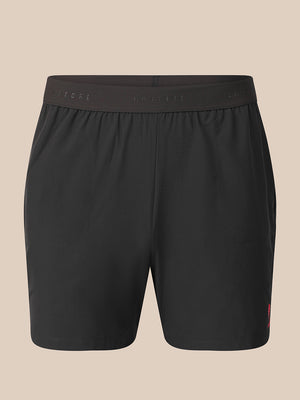 Black athletic shorts with an elastic waistband, shown against a solid beige background.