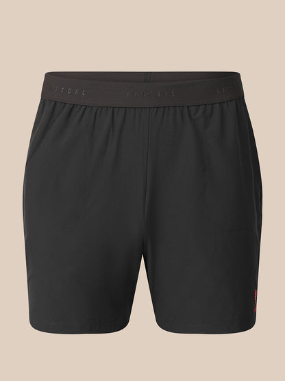 Black athletic shorts with an elastic waistband, shown against a solid beige background.
