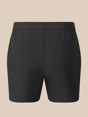 Black athletic shorts with a wide elastic waistband, shown flat against a solid beige background.