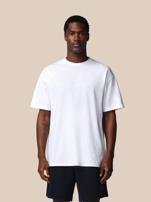 Man wearing a plain white t-shirt and black shorts on a beige background