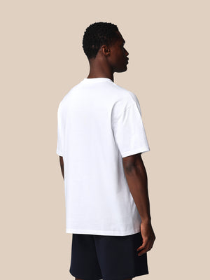 Person wearing a plain white t-shirt on a beige background