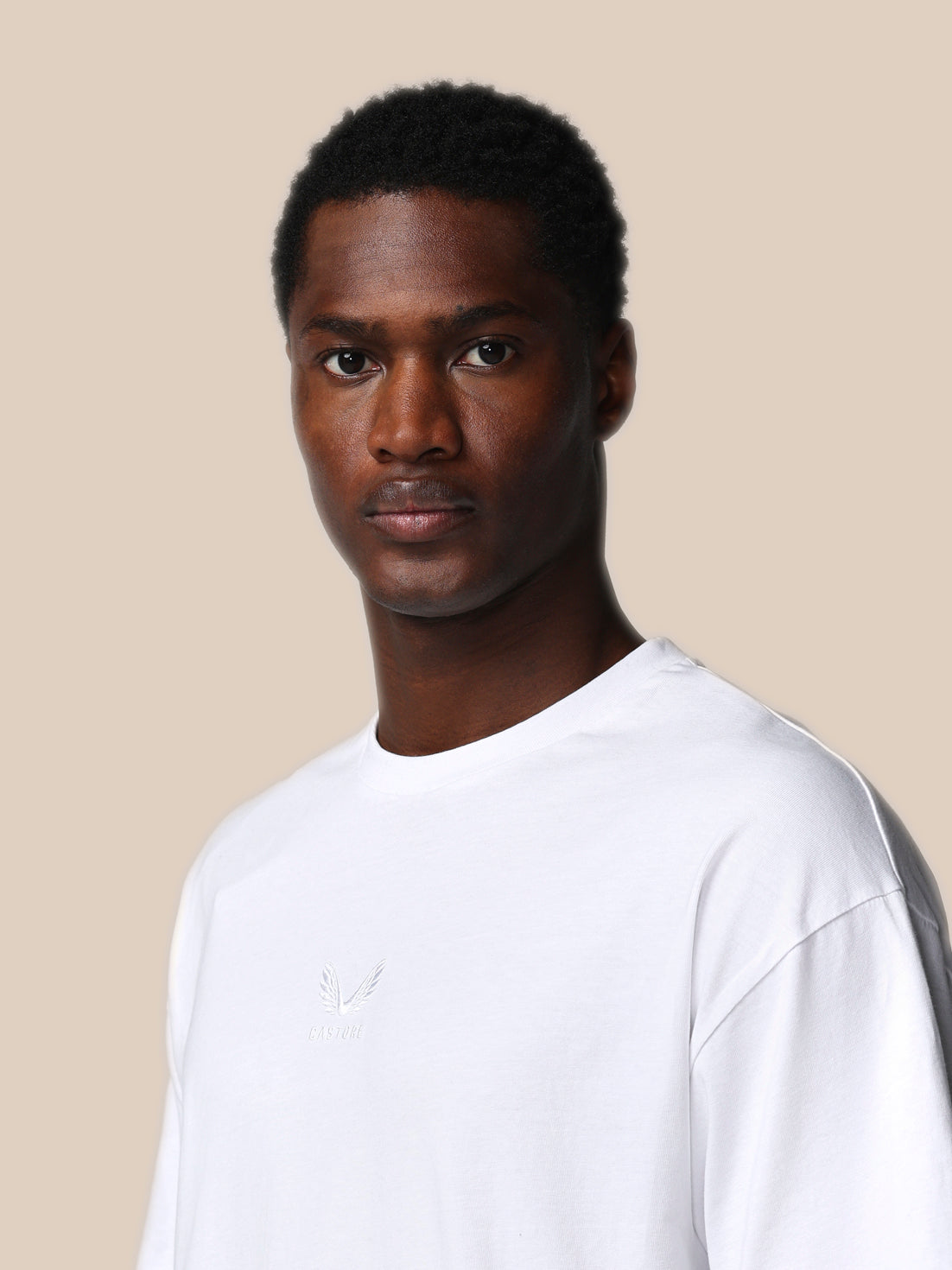 Man wearing a white t-shirt against a beige background