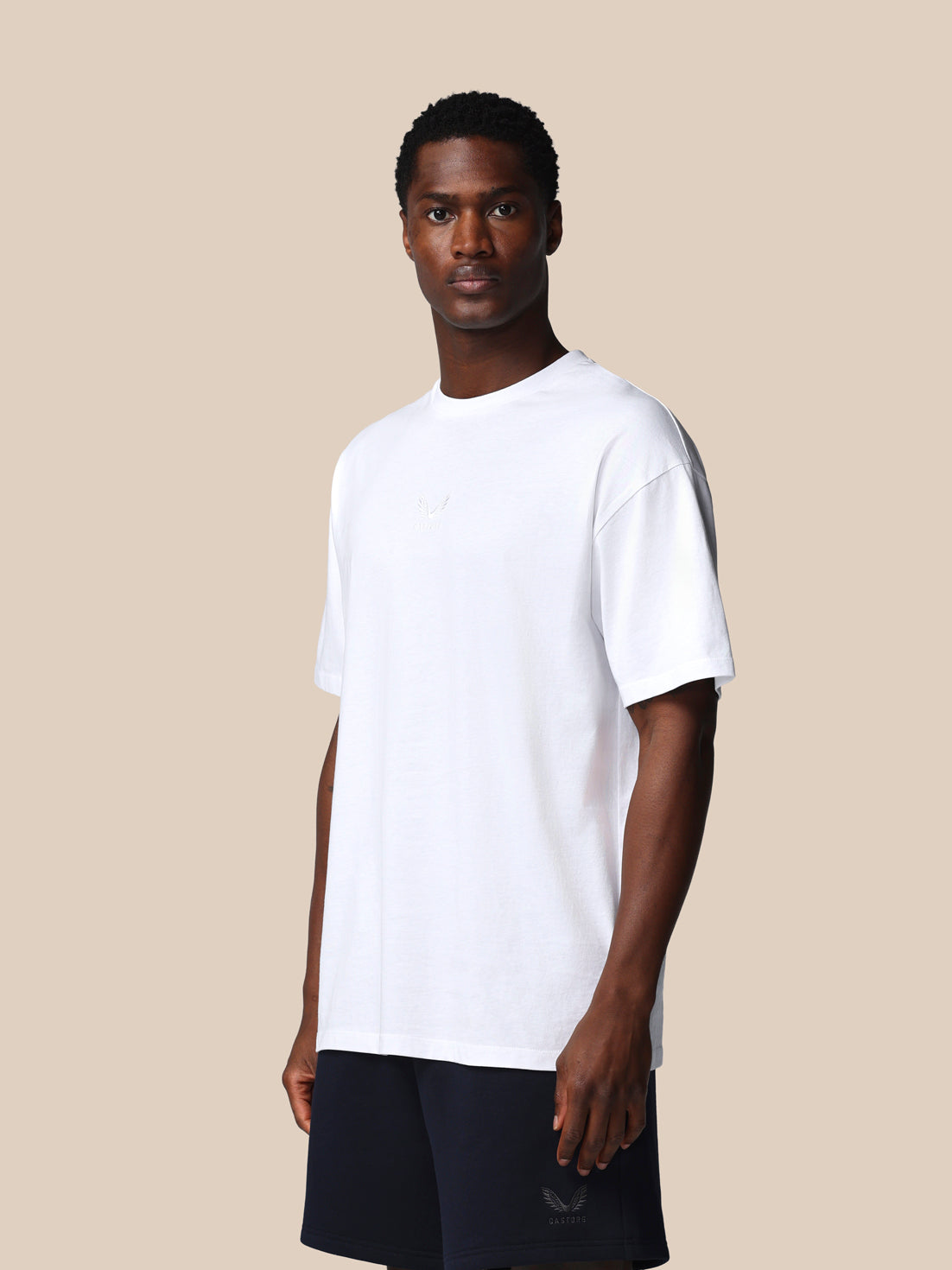 Man wearing a plain white t-shirt against a beige background