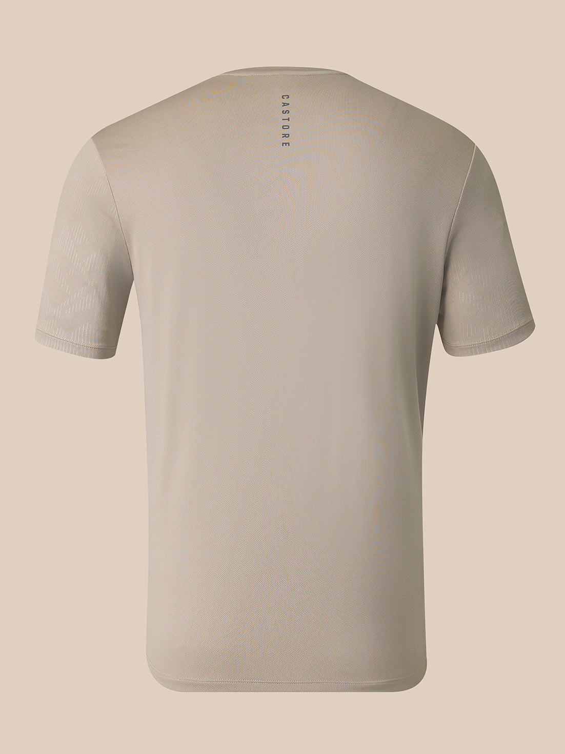 A light beige short-sleeve crewneck t-shirt shown from the back, featuring a small vertical 'CASTORE' logo printed in dark gray near the upper center back, set against a solid light beige background.