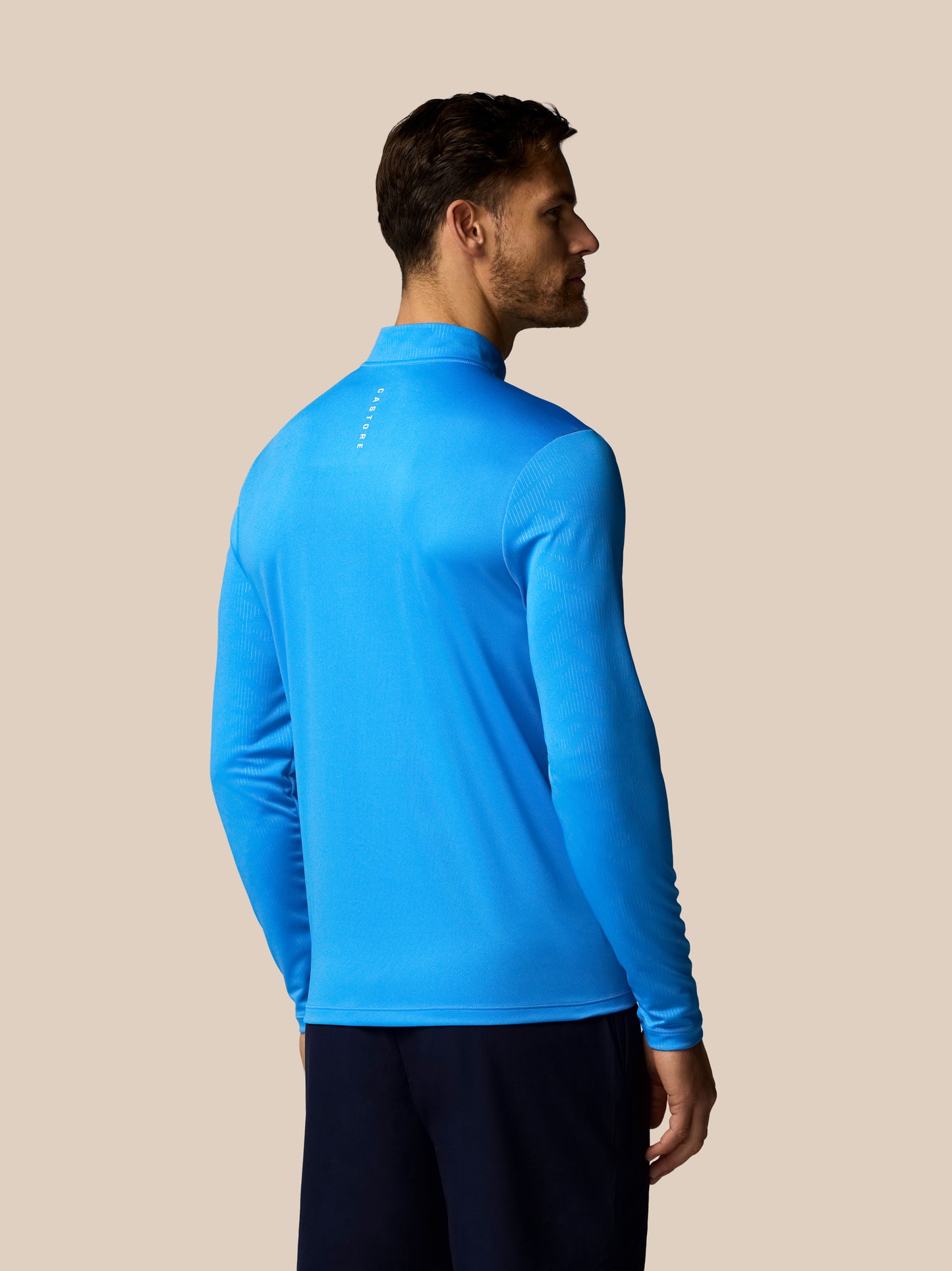 Back and side view of blue men's Adapt quarter zip long sleeve top with stand collar; Castore logo visible on the back.