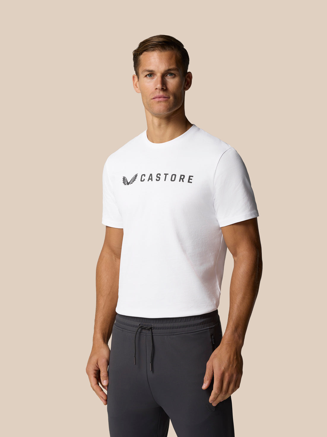 Male model wearing white Castore graphic T shirt with front wordmark.