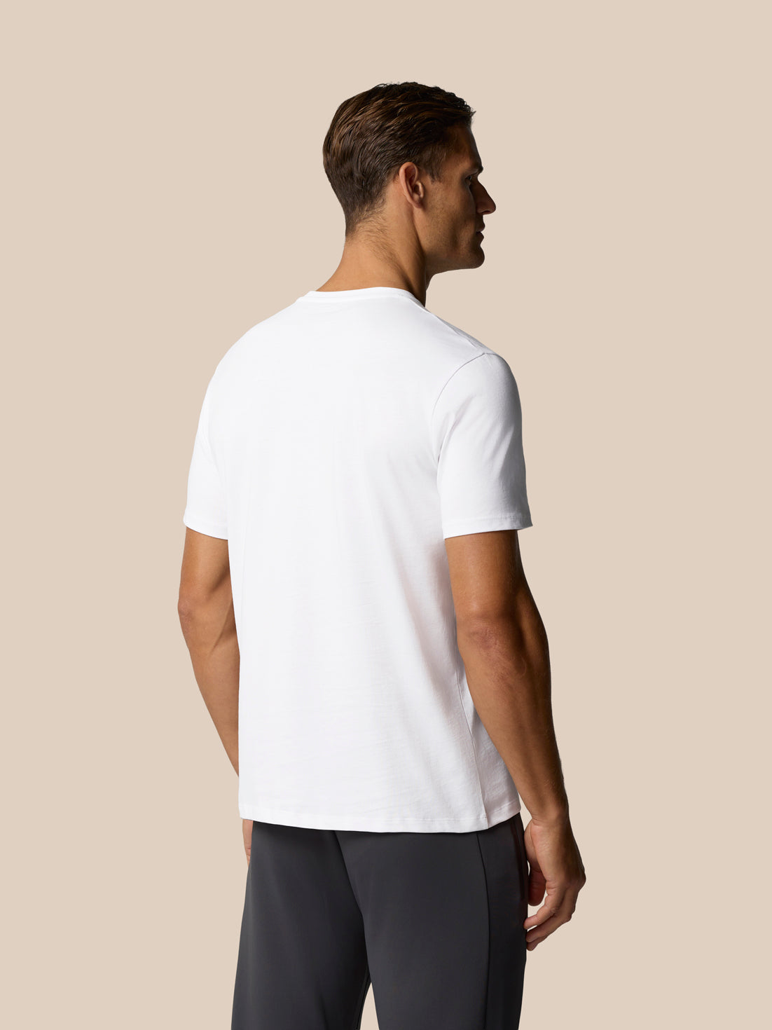 Male model wearing white Castore graphic T shirt, shown from the side with chest logo.