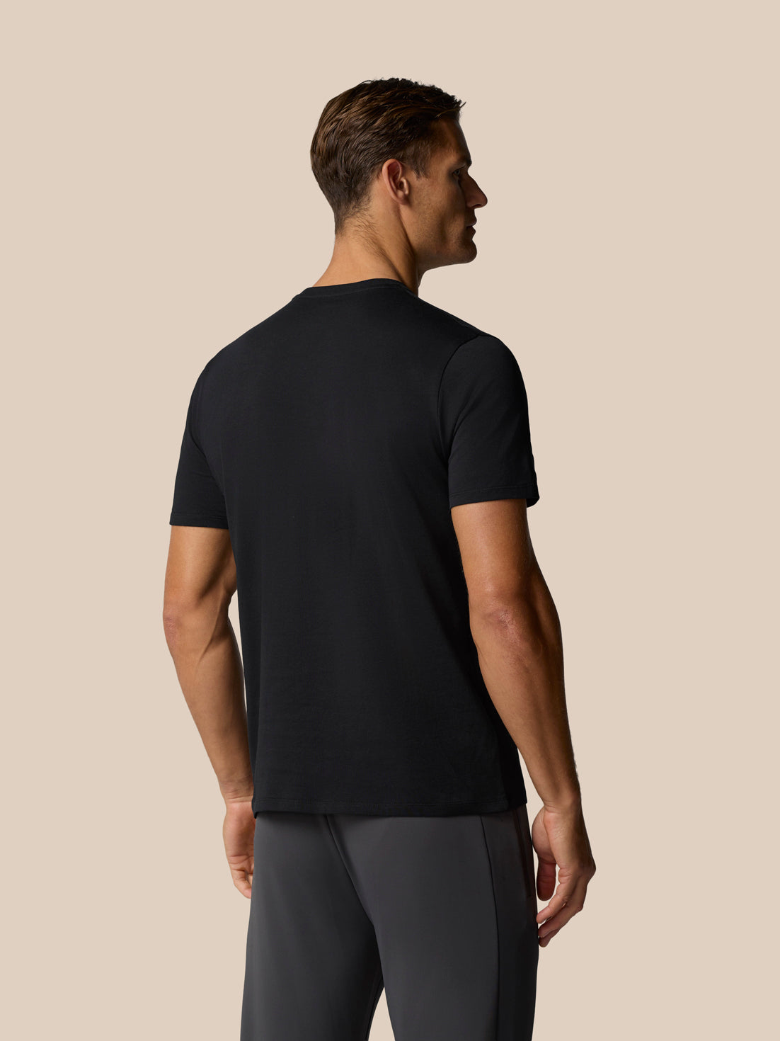 Back view of a man wearing a black Castore graphic lifestyle T-shirt