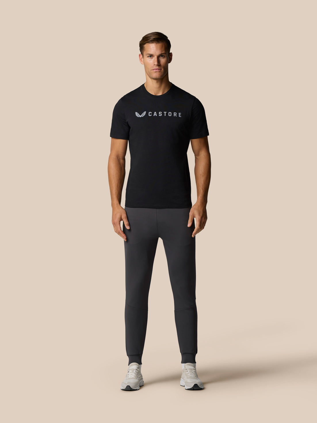 Full body shot of a man wearing a black Graphic Lifestyle T-Shirt with a front Castore logo.