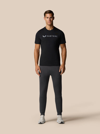Full body shot of a man wearing a black Graphic Lifestyle T-Shirt with a front Castore logo.