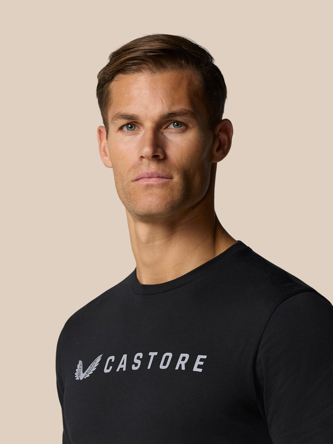 Full body shot of a man in a black Graphic Lifestyle T-Shirt with a large CASTORE chest logo.