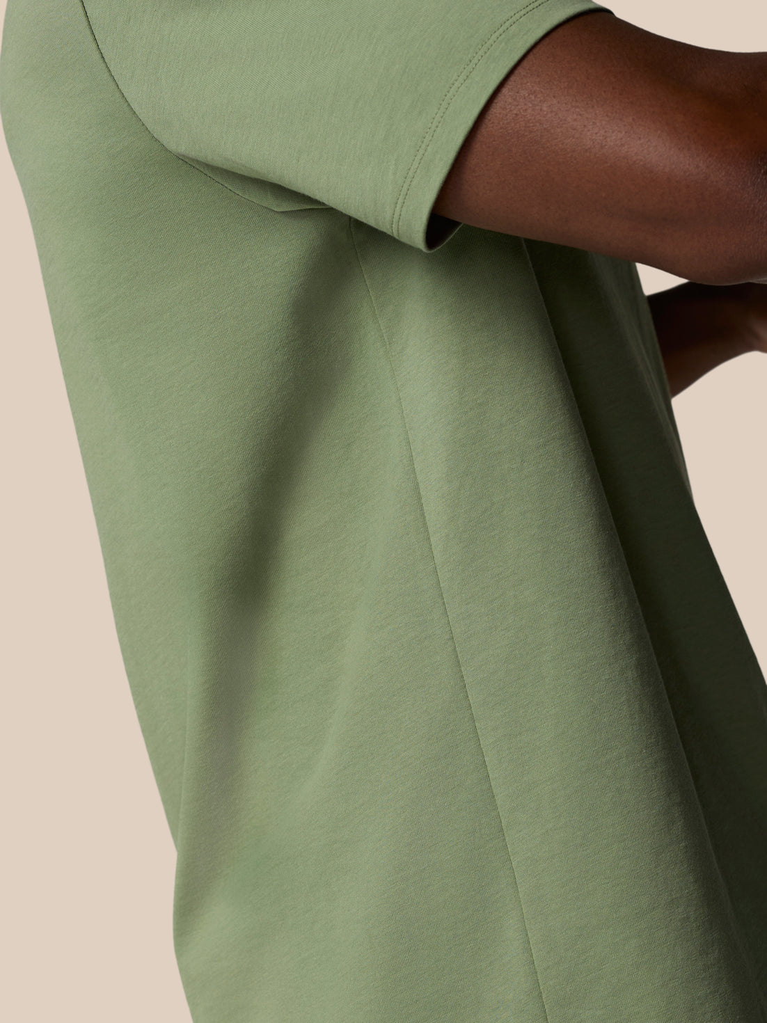 Close-up of thyme green knit fabric and sleeve seam from a short sleeve Castore T shirt