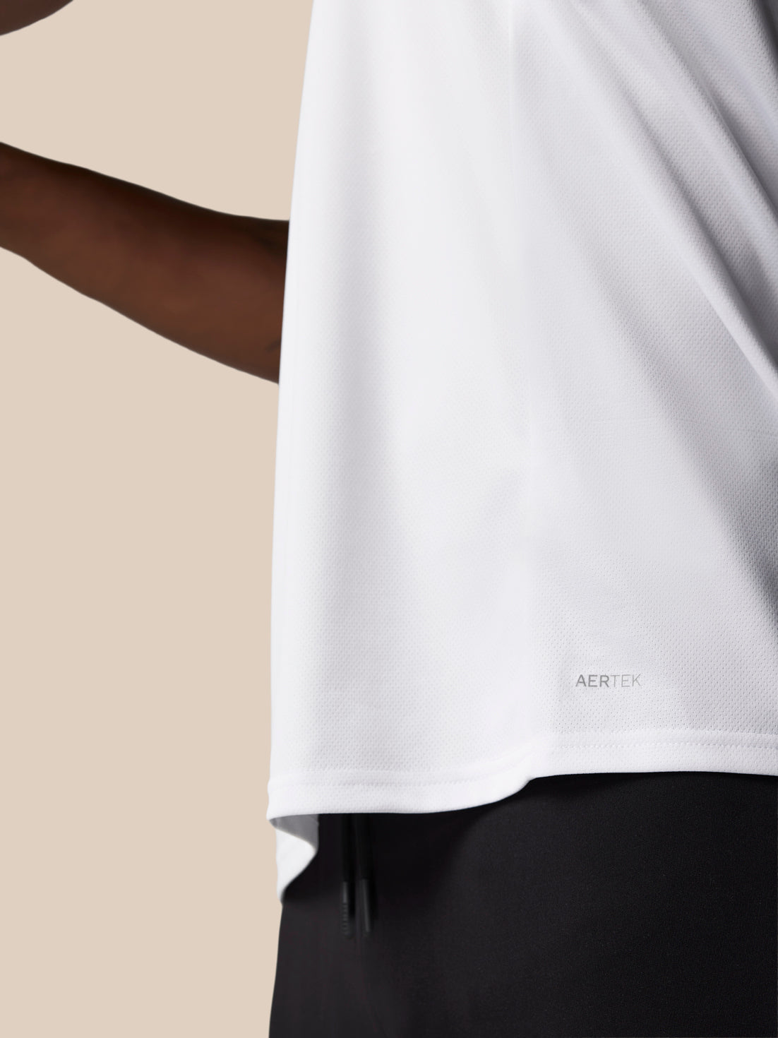 Close-up of white graphic training T shirt fabric showing AerTek moisture-wicking texture and a small AERTEK label at the hem