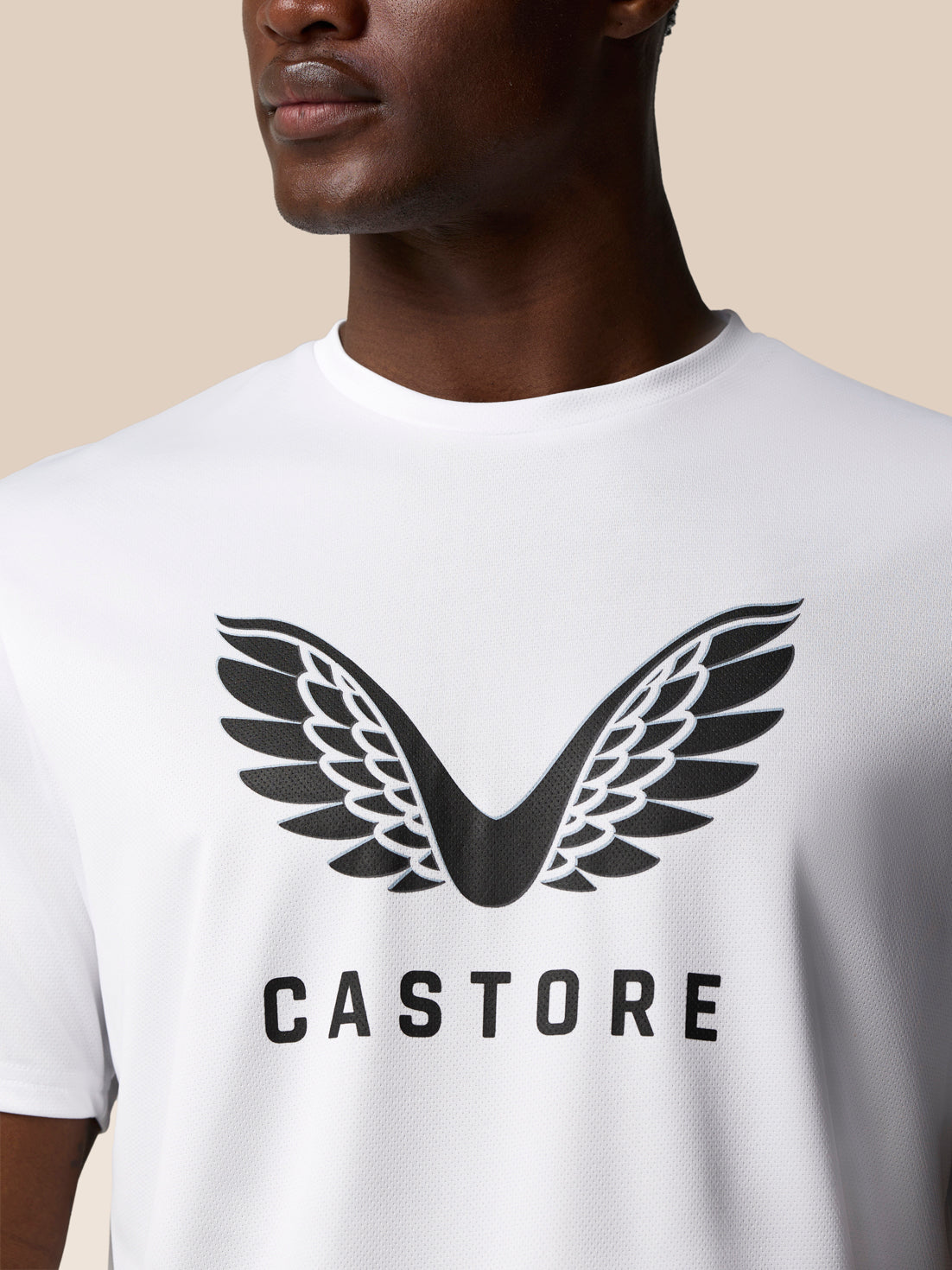Model wearing white graphic training T shirt with large Castore wing logo on the chest