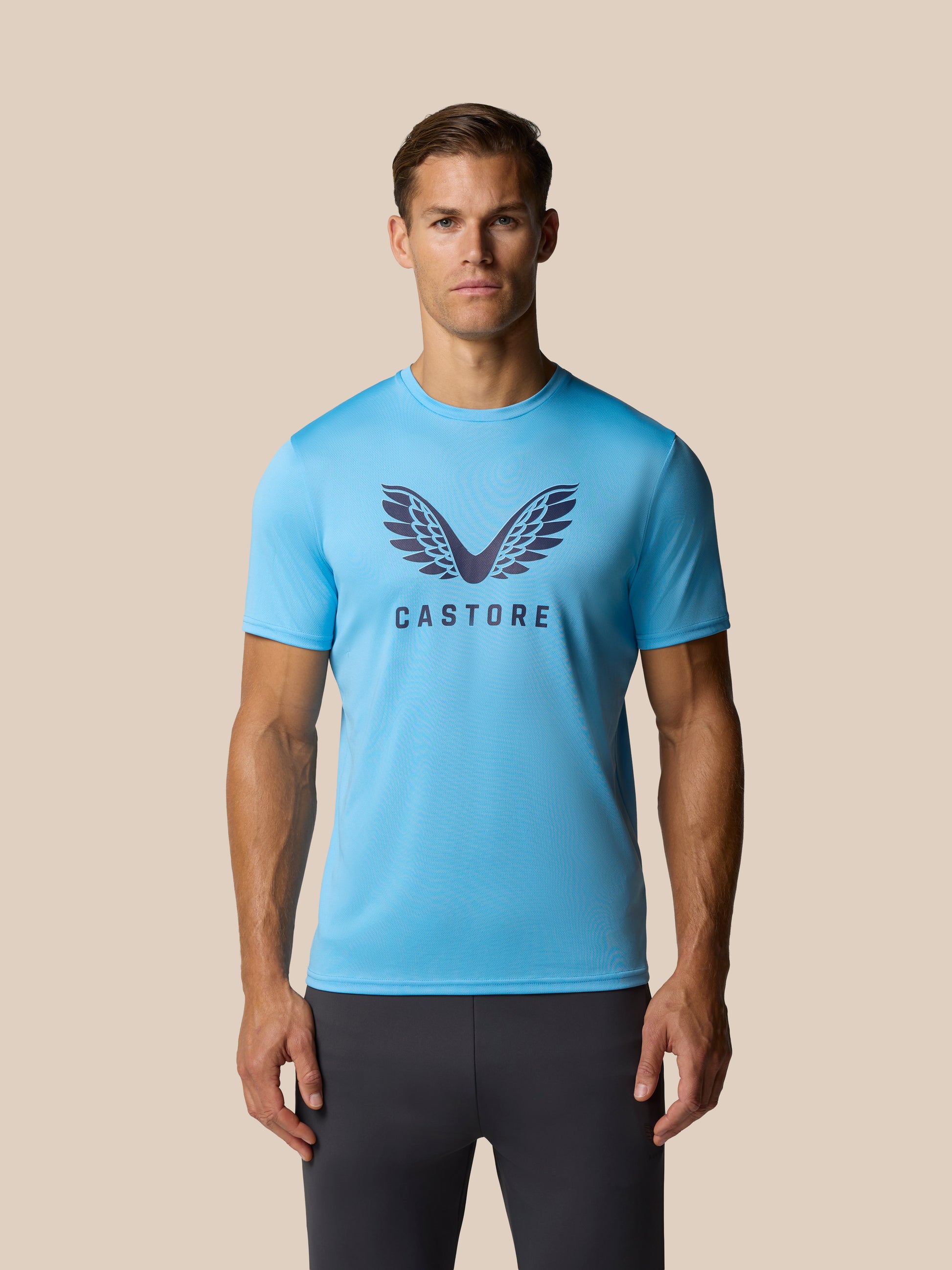 Male model wearing light blue graphic Castore T shirt with wing logo on the chest