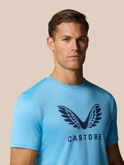 Front view of a man in a light blue graphic training T shirt with Castore wings logo on chest