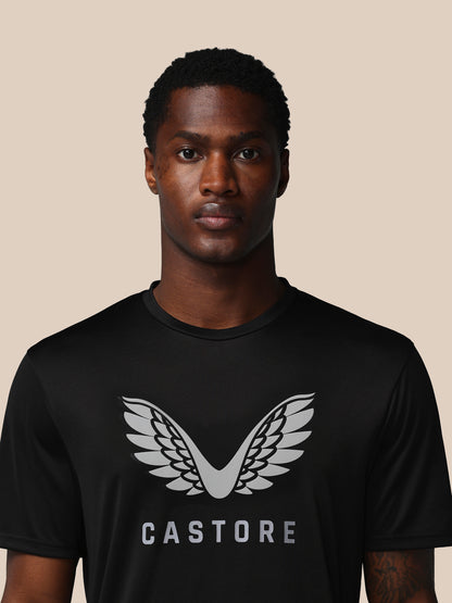 Man wearing a black t-shirt with a white logo and 'CASTORE' text on a beige background