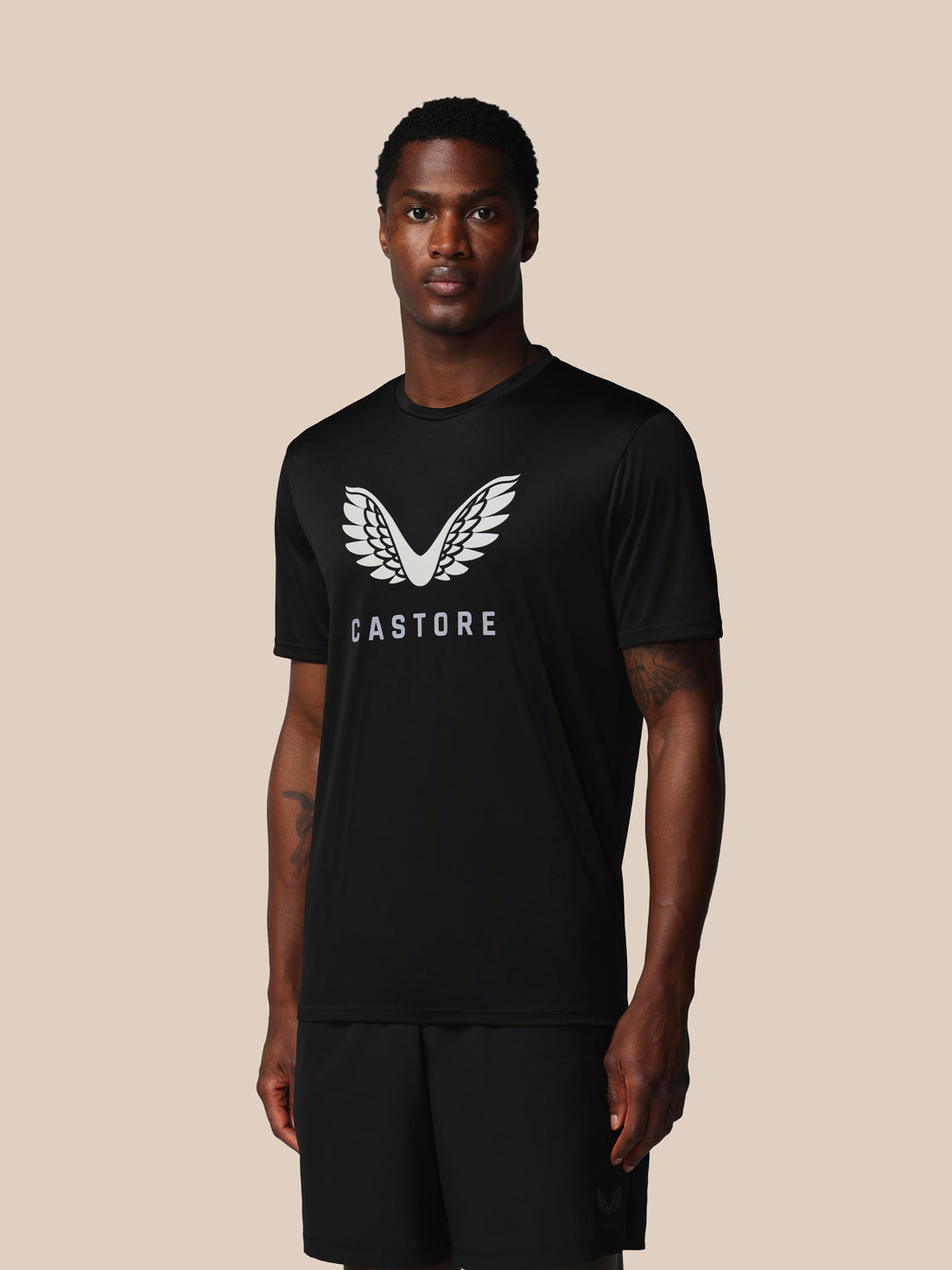 Person wearing a black t-shirt with a logo on a beige background