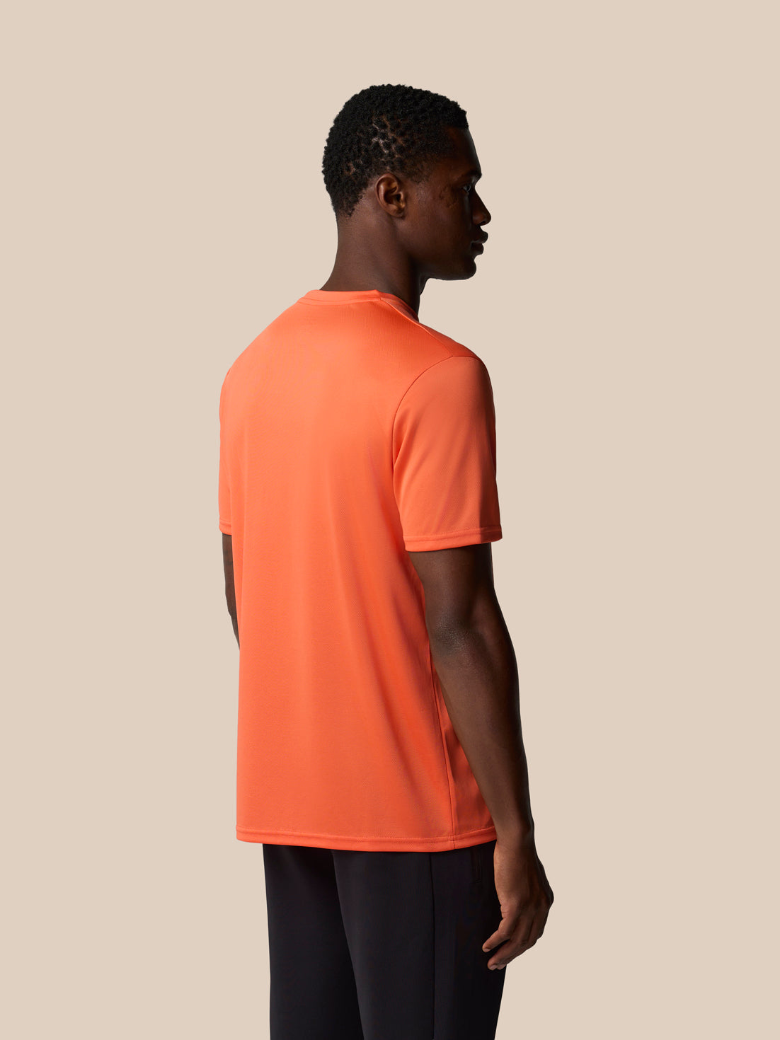 Back view of a bright orange graphic training T shirt worn by a male model