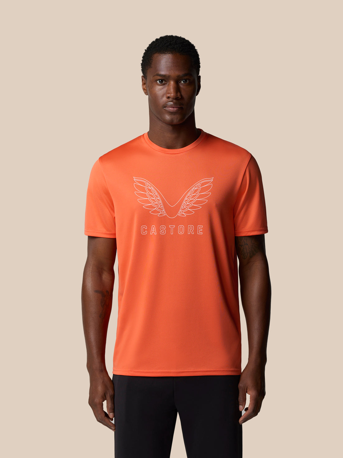 Male model wearing bright orange graphic training T shirt with wings logo on chest