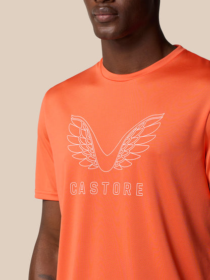 Close-up of bright orange Castore graphic training T shirt showing large white wing logo and CASTORE text across the chest.