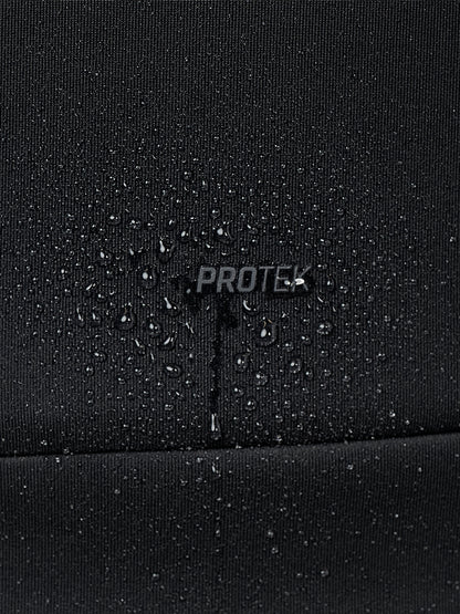 Close-up of a black waterproof fabric with water droplets beaded on the surface and a central 'PROTEK' logo, showing water beading over the text.