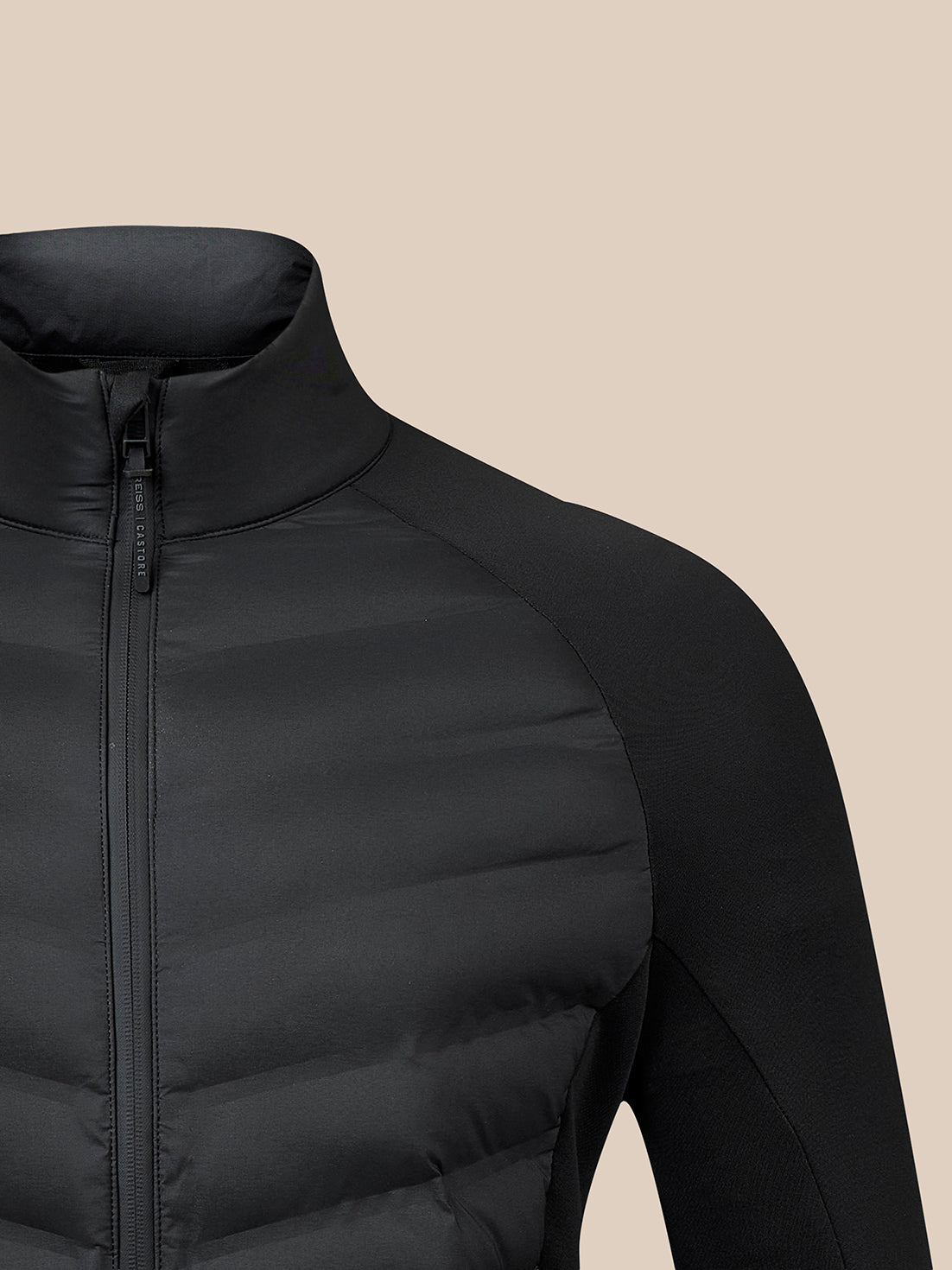 Close-up of a black puffer jacket with a high collar and front zipper, shown against a solid beige background.
