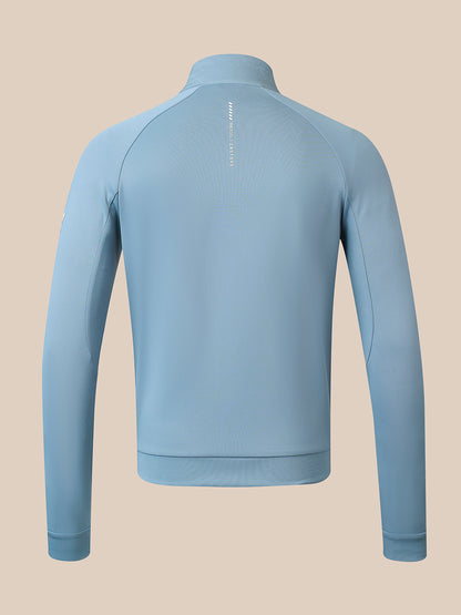 A light blue long-sleeve athletic quarter-zip jacket shown from the back, featuring a subtle vertical zipper detail and a small white logo on the upper back, set against a solid beige background.