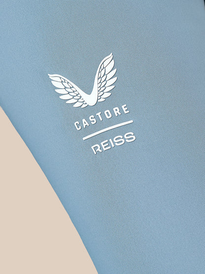 Close-up of a light blue athletic fabric with a white embroidered wing logo and the text 'CASTORE REISS' printed on it.