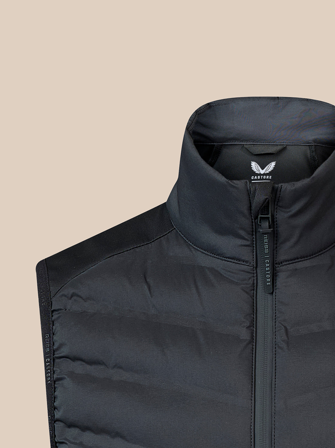 Upper torso of a black high collar gilet with branded zipper and Castore label.