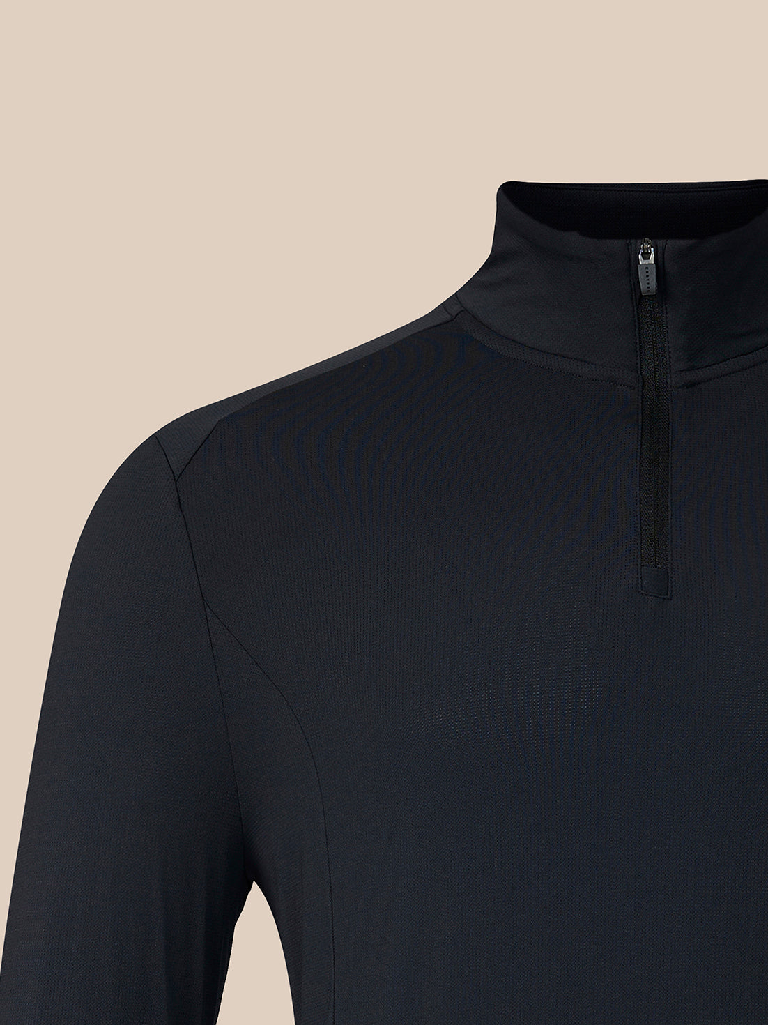 Close-up of a dark navy long-sleeve quarter-zip athletic top, showing the collar, zipper, and shoulder seam against a solid beige background.