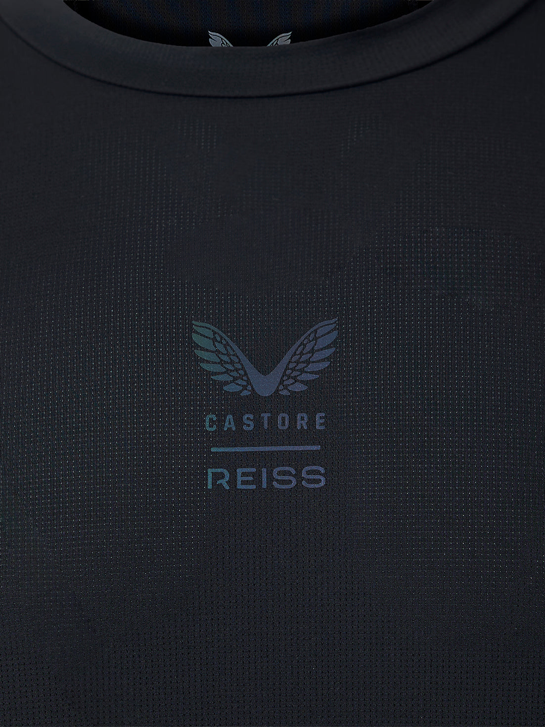 Close-up of a dark navy textured knit top with a subtle tonal Castore Reiss wing logo and text on the chest.