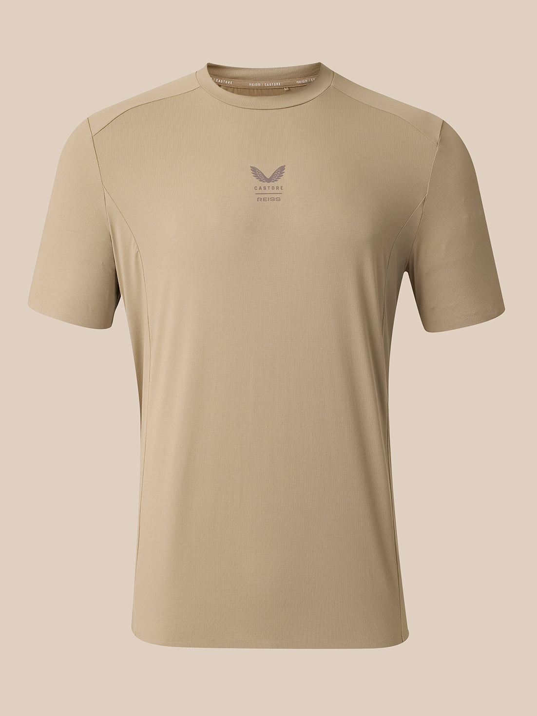 A beige short-sleeve athletic t-shirt with a small gray winged logo and 'CASTORE' text printed on the center chest, displayed on a solid beige background.