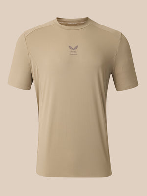 A beige short-sleeve athletic t-shirt with a small gray winged logo and 'CASTORE' text printed on the center chest, displayed on a solid beige background.