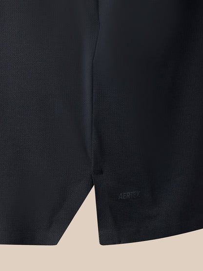 Close-up of a dark athletic fabric garment corner showing a small tonal AERTEK logo on a light beige background.