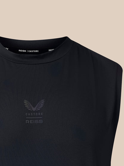 Close-up of a sleeveless black top with a crew neck and subtle Castore Reiss wing logo on the chest, set against a solid beige background.